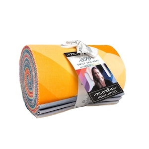 May include: A rolled fabric bundle with a vibrant yellow and orange geometric design. The bundle is tied with a white ribbon and a tag featuring a woman's image and the words "echo" and "moda fabrics + supplies."