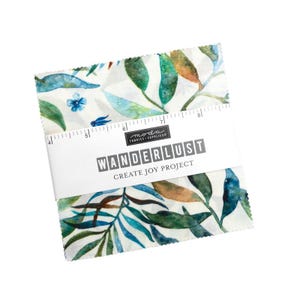 May include: A white fabric square with a watercolor pattern of blue, green, and brown leaves. The fabric is labeled "Wanderlust Create Joy Project" by Moda Fabrics.