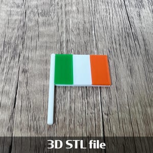 Può includere: Una piccola bandiera irlandese con un'asta bianca. La bandiera presenta strisce verticali verdi, bianche e arancioni. Il testo "3D STL file" è visibile nella parte inferiore dell'immagine.