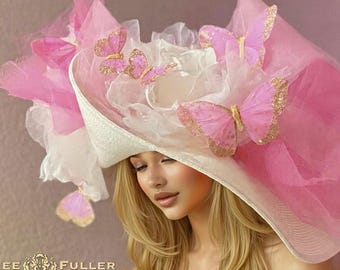 May include: A wide-brimmed white hat adorned with layers of pink and white tulle fabric and several pink butterfly decorations with gold glitter accents. The text "AIMEE FULLER" is printed in the bottom left corner of the image.