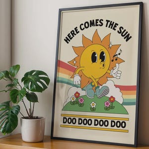 May include: A framed poster with a retro cartoon sun character. The sun is yellow with a smiling face, wearing blue shoes, and standing on a green hill with flowers. The text "HERE COMES THE SUN" and "DOO DOO DOO DOO" are displayed.