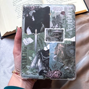 Puede incluir: Funda protectora transparente con un diseño de collage que presenta una espada, un grifo y un ala de dragón. El diseño incorpora el texto "STARLING" y "Even if we are kingdoms apart, you are mine."