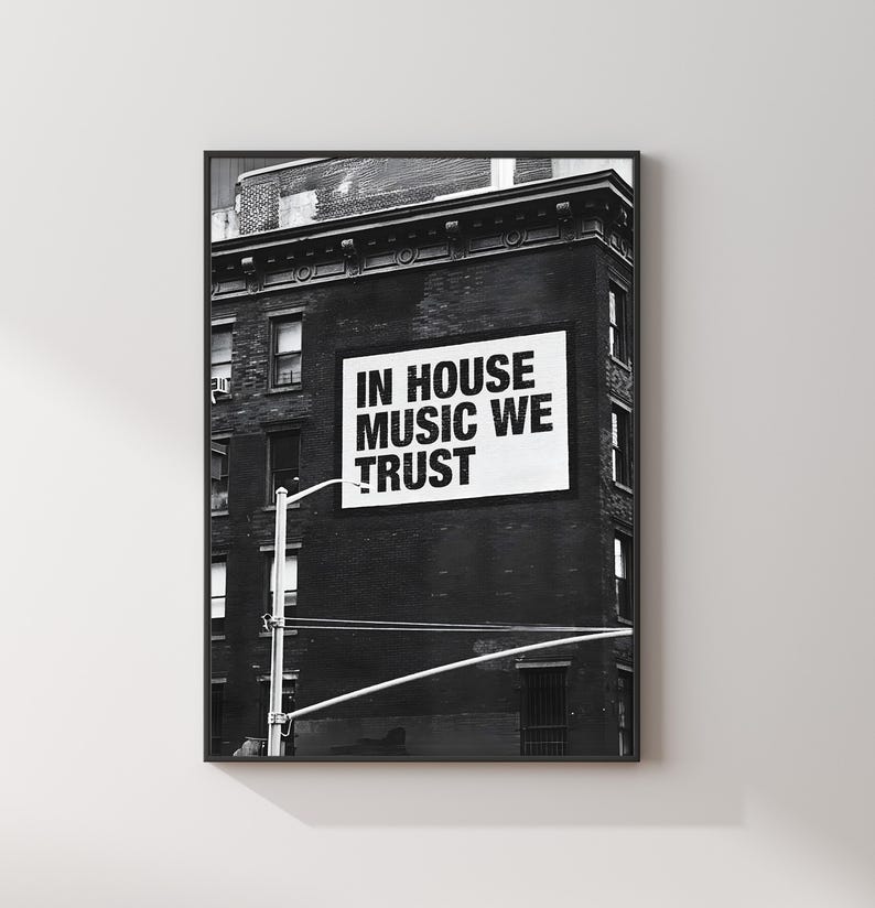 May include: Black and white framed print featuring a building facade with a sign that reads "IN HOUSE MUSIC WE TRUST". The image is a photograph of a city scene, with a street light in the foreground.