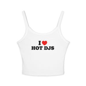 May include: White tank top with thin straps. The text "I ♥ HOT DJS" is printed in black with a red heart symbol. The top is made of a ribbed material.