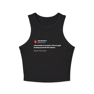 Puede incluir: Top corto negro con cuello redondo y un tuit impreso. El tuit dice "unfortunately for my haters i will once again be living my best life this weekend" de John Summit. El tuit fue publicado el 10 de febrero de 2023.