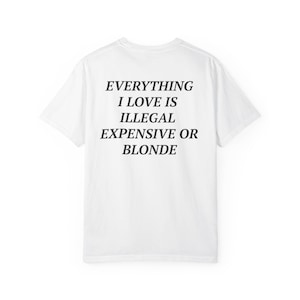 May include: White t-shirt with the text "EVERYTHING I LOVE IS ILLEGAL EXPENSIVE OR BLONDE" in black, centered on the back. The shirt has a classic crew neck and short sleeves, suitable for casual wear.
