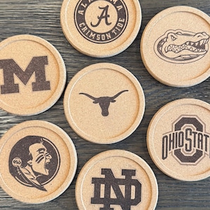 May include: Set of seven round cork coasters featuring various college logos. The logos include Alabama Crimson Tide, Florida Gators, Texas Longhorns, Michigan Wolverines, Ohio State Buckeyes, Notre Dame Fighting Irish, and Florida State Seminoles.