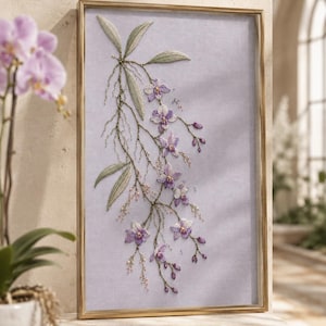 May include: A rectangular framed wall art piece featuring intricate embroidery of purple orchid flowers and green leaves on a light lavender fabric background. The artwork is encased in a thin, metallic gold frame, showcasing detailed floral stitching.
