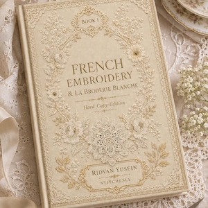 Puede incluir: Un libro de tapa dura titulado French Embroidery & La Broderie Blanche, Book 1, de Ridvan Yusein Stitchesly. La cubierta de color crema presenta intrincados patrones florales y de encaje en relieve de tono dorado, con elegantes bordes decorativos.
