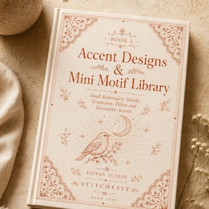 Może przedstawiać: Książka w twardej oprawie zatytułowana Accent Designs & Mini Motif Library autorstwa Ridvana Yuseina Stitchesly. Kremowa okładka zawiera miedziane ilustracje ptaka, półksiężyca i kwiatowe obramowania z motywami do haftowania.