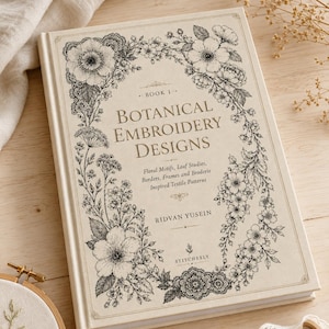 Könnte beinhalten: Cremefarbenes Buch mit dem Titel "Botanical Embroidery Designs" mit floralen Illustrationen. Das Cover zeigt einen Kranz aus detaillierten schwarz-weißen Blumen. Das Buch enthält den Namen des Autors, Ridvan Yusein, und den Verlag, Stitchesly. Thema: Stickerei.