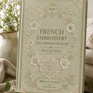 May include: A hardcover book titled French Embroidery & La Broderie Blanche Book 3 by Ridvan Yusein Stitchesly. The sage green cover features intricate cream-colored floral and lace-like embroidery patterns framing the central text.