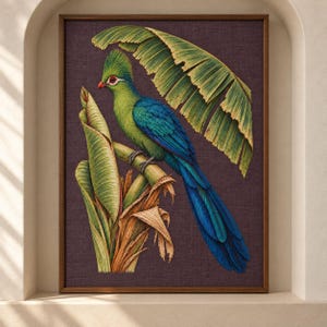 May include: A framed wall art print featuring a vibrant green and blue turaco bird perched on a plant stem. The bird has a prominent crest and red eye markings. Large, textured green banana leaves arch over the bird against a dark purple background.