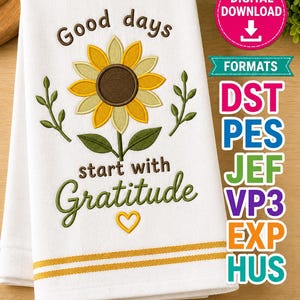 May include: White kitchen towel with an embroidered sunflower and the words "Good days start with Gratitude." The design includes a yellow heart and green leaves. The towel also has two yellow stripes.