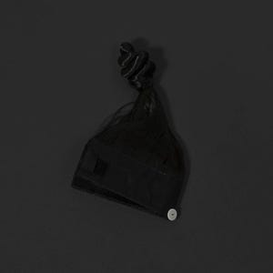 K&ouml;nnte beinhalten: Ein schwarzes Haaraccessoire, m&ouml;glicherweise eine Per&uuml;ckenkappe oder ein Haarteil, mit Knopfverschluss. Das Accessoire hat eine dunkle, strukturierte Basis und einen Abschnitt dunkler Haare, die zu einem Dutt frisiert sind. Der Hintergrund ist einfarbig dunkelgrau.