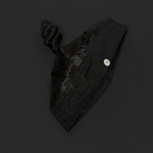 K&ouml;nnte beinhalten: Eine schwarze Kopfbedeckung mit einem geknoteten Oberteil und einem Knopfverschluss. Die Kopfbedeckung scheint aus einem strukturierten Stoff, m&ouml;glicherweise Mesh, gefertigt zu sein. Der Hintergrund ist einfarbig schwarz.