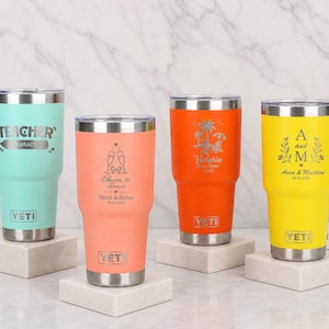 May include: Four stainless steel YETI tumblers in mint green, coral, orange, and yellow. Each tumbler features a clear lid, a silver base, and custom laser-engraved designs including text like TEACHER, Cheers to Forever, and names with dates.