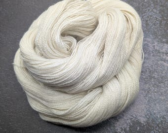 May include: A ball of cream-coloured yarn, tightly wound. The yarn has a soft appearance and is likely made from natural fibres. The neutral colour and texture suggest it could be used for knitting or crochet projects, suitable for various craft creations.