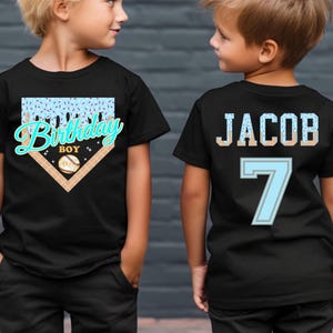 May include: Two black t-shirts with baseball-themed designs. One shirt says "Birthday Boy" with a baseball graphic. The other shirt has the name "Jacob" and the number "7" on the back, in a baseball jersey style.