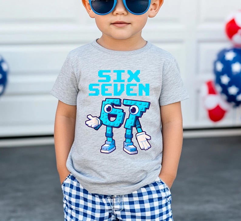May include: A gray t-shirt with the words "SIX SEVEN" in light blue pixelated font. Below, the numbers 6 and 7 are depicted as cartoon characters with blue bodies, white gloves, and blue shoes. The shirt is worn by a child.