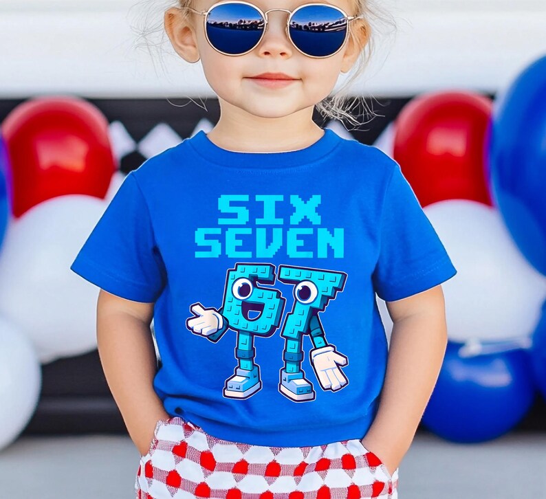 May include: A blue t-shirt with the words "SIX SEVEN" in pixelated font. Below the text are the numbers 6 and 7 designed as cartoon characters with arms, legs, and shoes. The child is wearing sunglasses and red and white checkered shorts.