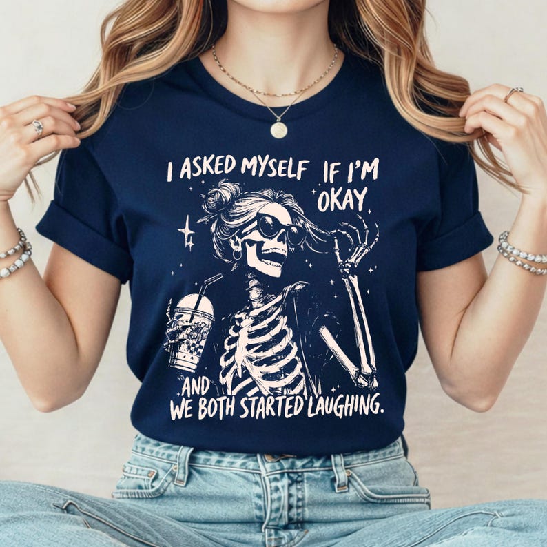 May include: Navy blue t-shirt with a skeleton graphic wearing sunglasses and holding a drink. The text reads "I asked myself if I'm okay. And we both started laughing."