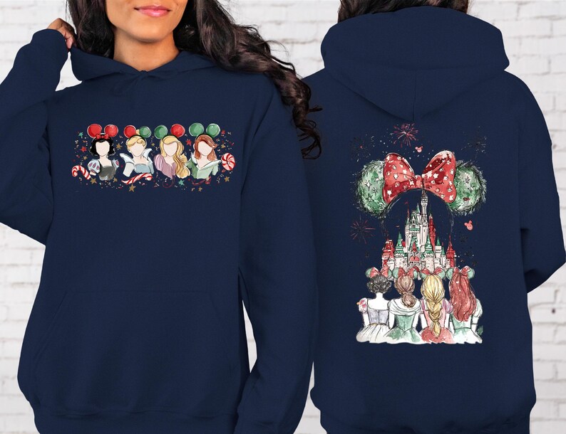 May include: Navy blue hooded sweatshirt featuring a colorful graphic of Disney princesses on the front and back. The front design shows four princesses with Mickey Mouse ears and candy canes. The back design features a castle and fireworks.
