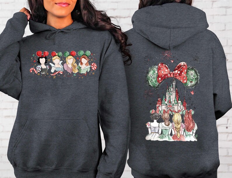 May include: Dark gray hoodie featuring a colorful illustration of Disney princesses on the front and back. The front design shows four princesses with candy canes and mouse ears. The back features a castle and mouse ears with a red bow.
