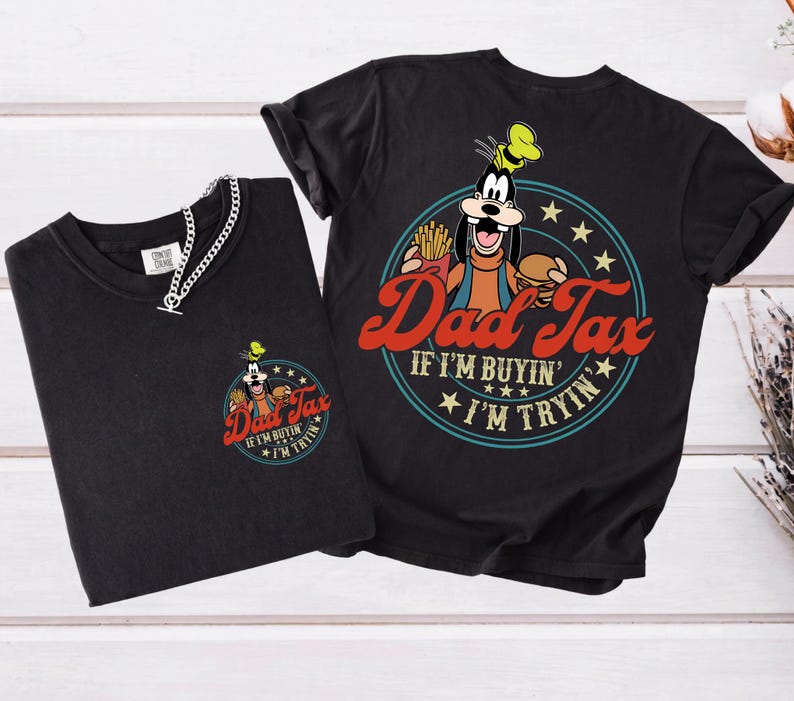 May include: Two black t-shirts with a graphic of Goofy holding a burger and fries, with the text "Dad Tax" in red and the phrase "If I'm buyin', I'm tryin'". One shirt has a small version of the graphic on the chest.