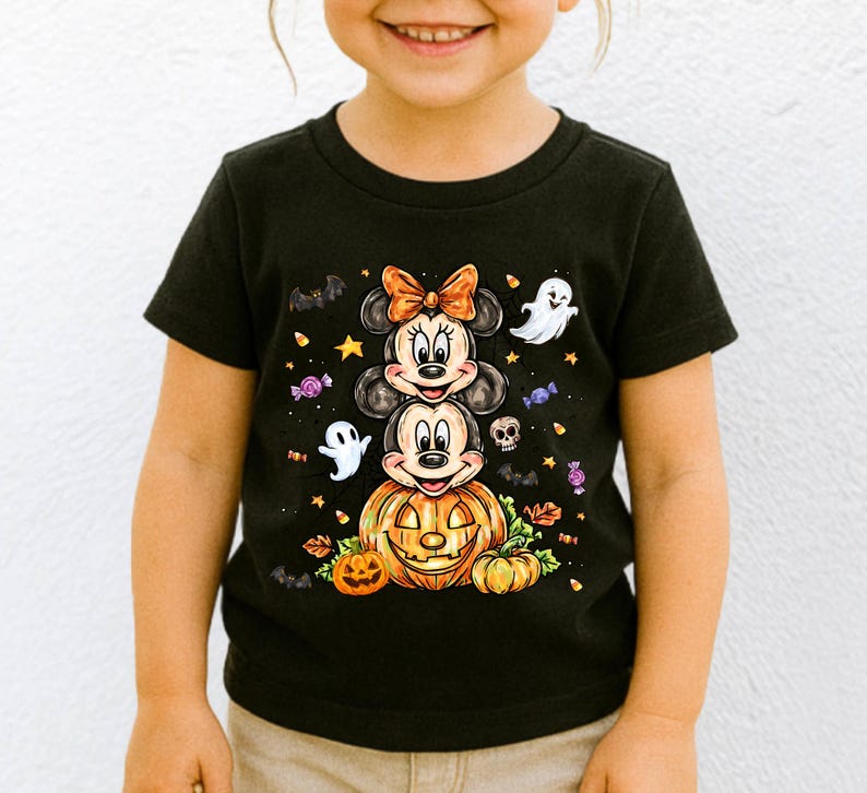 Puede incluir: Camiseta negra con un dise&ntilde;o de Halloween. El dise&ntilde;o muestra a los personajes de Minnie y Mickey Mouse apilados sobre una calabaza, rodeados de fantasmas, murci&eacute;lagos y caramelos. Los personajes llevan disfraces de Halloween.