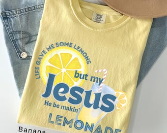 May include: A yellow t-shirt with the text "Life gave me some lemons but my Jesus He be makin' Lemonade" and a graphic of a lemon and a glass of lemonade. The shirt is folded on top of blue jeans.