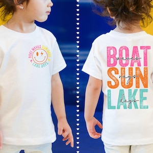 May include: White t-shirt with a summer-themed design. The front has a smiley face graphic and the words "Boat Waves Summer Lake Days." The back displays "Boat Waves Sun Rays Lake Days" in pink, orange, and teal.