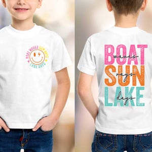 May include: White t-shirt featuring the text "Boat Waves Sun Rays Lake Days" in a smiley face design on the front. The back of the shirt displays the words "Boat Waves Sun Rays Lake Days" in vibrant, stacked lettering.