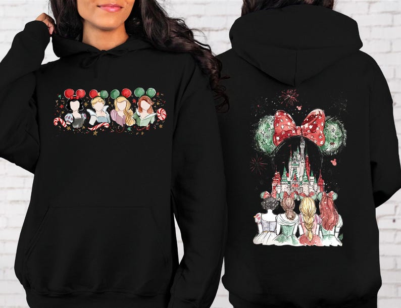 May include: Black hooded sweatshirt featuring a colorful graphic of Disney princesses with holiday-themed Minnie Mouse ears and a castle design. The front shows the princesses, while the back displays the castle and fireworks.