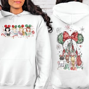 May include: White hooded sweatshirt featuring a watercolor design of Disney princesses wearing Mickey Mouse ears. The front shows four princesses, while the back displays a castle and fireworks with a Mickey Mouse ear design.