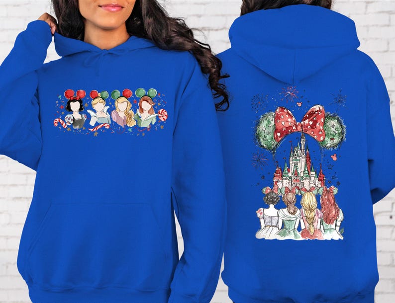 May include: Royal blue hoodie featuring a watercolor design of Disney princesses on the front and back. The front displays four princesses with Mickey Mouse ears and candy canes. The back showcases Cinderella's castle and fireworks.