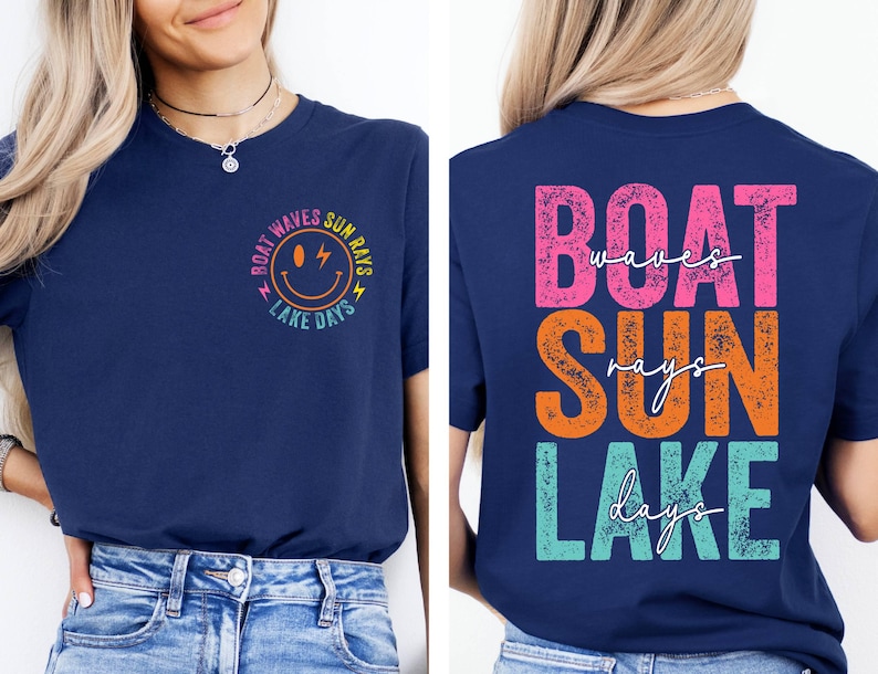 May include: A navy blue t-shirt with a vibrant graphic design. The front displays a smiley face and the words "Boat Waves Sun Rays Lake Days". The back of the shirt has the words "Boat Waves Sun Rays Lake Days" in a stacked layout.