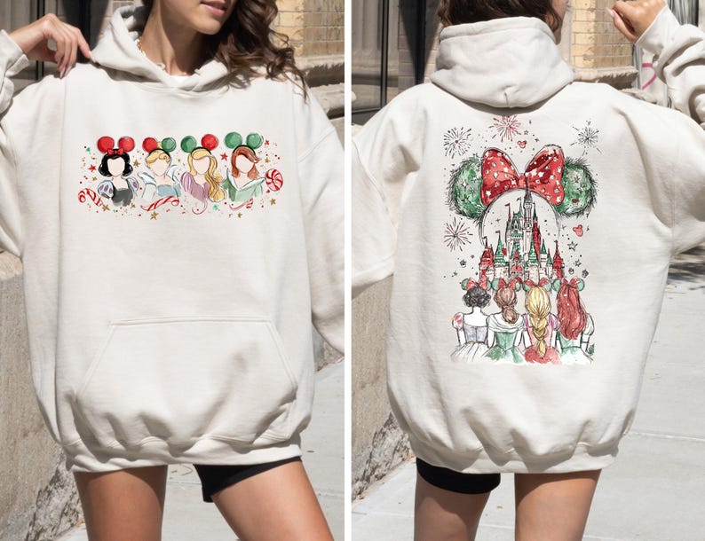 May include: Cream-colored hoodie featuring a watercolor design of Disney princesses on the front and back. The front displays four princesses with festive headbands. The back showcases a castle and fireworks.