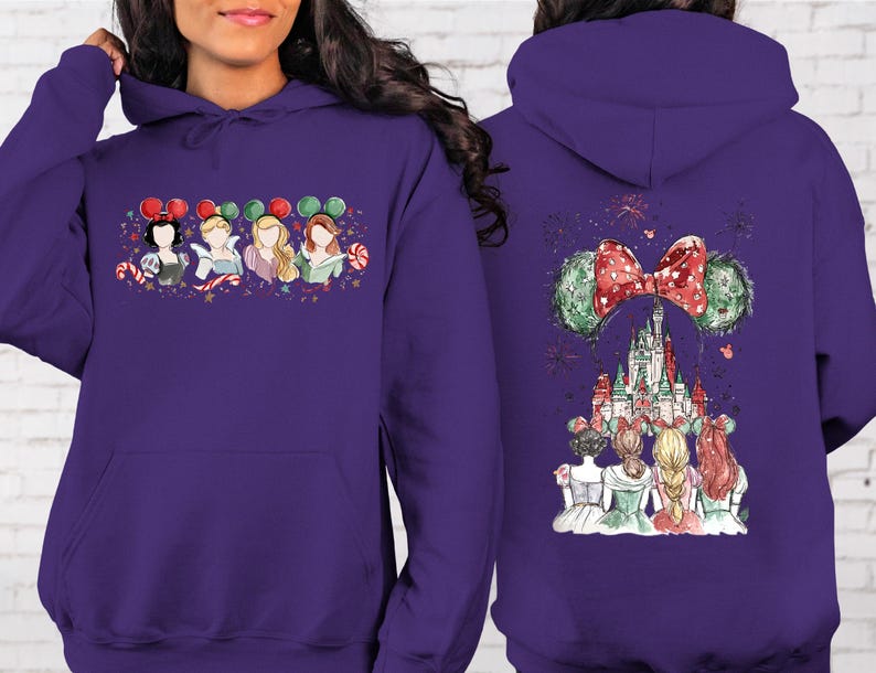 May include: A purple hooded sweatshirt featuring a front graphic of four cartoon princesses wearing holiday-themed mouse ears. The back of the sweatshirt displays a castle scene with a large bow and mouse ears.