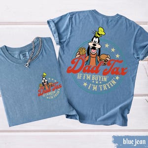 May include: Two blue jean t-shirts. One shirt has a small graphic of Goofy with the text "Dad Tax" and "If I'm buyin', I'm tryin'". The other shirt has a larger graphic of Goofy with the same text. A silver chain necklace is on the first shirt.