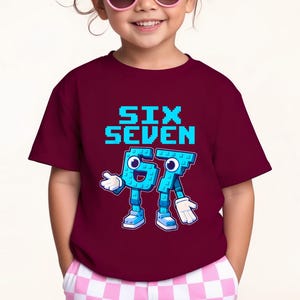 May include: A maroon t-shirt featuring the text "SIX SEVEN" in pixelated blue letters. Below, the numbers "67" are depicted as cartoon characters with blue bodies, white gloves, and shoes. The shirt is worn by a child.