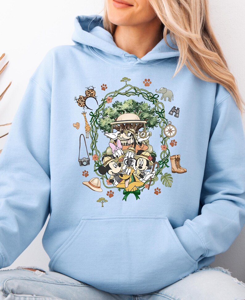 Peut inclure: Sweat &agrave; capuche bleu clair avec un motif sur le th&egrave;me du safari. Le design comprend des personnages de dessins anim&eacute;s, un v&eacute;hicule de safari et des ic&ocirc;nes de safari telles qu'une girafe, un &eacute;l&eacute;phant et des jumelles. Le motif est entour&eacute; d'une couronne de feuilles et d'empreintes de pattes.
