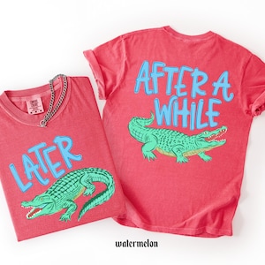 May include: Two red t-shirts with the text "LATER" and "AFTER A WHILE" in blue, along with a green alligator graphic. The shirts are made of a soft material and are a watermelon color.