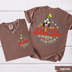 May include: Espresso-colored t-shirts with a graphic of a cartoon dog holding a burger and fries, with the text "Dad Tax" and "If I'm buyin' I'm tryin'". One shirt has a chain necklace.