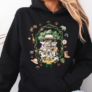 Peut inclure: Sweat &agrave; capuche noir avec un motif sur le th&egrave;me du safari. Le design comprend des personnages de dessins anim&eacute;s, un v&eacute;hicule de safari et des ic&ocirc;nes de safari telles qu'une girafe, un &eacute;l&eacute;phant et une boussole. Le sweat-shirt a une poche kangourou et une capuche &agrave; cordon.