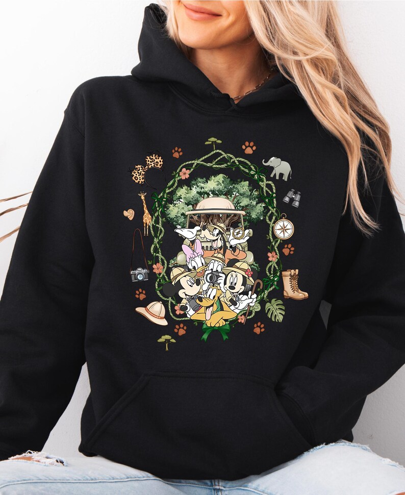 Peut inclure: Sweat &agrave; capuche noir avec un motif sur le th&egrave;me du safari. Le design comprend des personnages de dessins anim&eacute;s, un v&eacute;hicule de safari et des ic&ocirc;nes de safari telles qu'une girafe, un &eacute;l&eacute;phant et une boussole. Le sweat-shirt a une poche kangourou et une capuche &agrave; cordon.