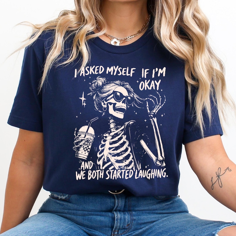 May include: Navy blue t-shirt featuring a skeleton wearing sunglasses and holding a beverage. The graphic includes the text "I asked myself if I'm okay and we both started laughing."