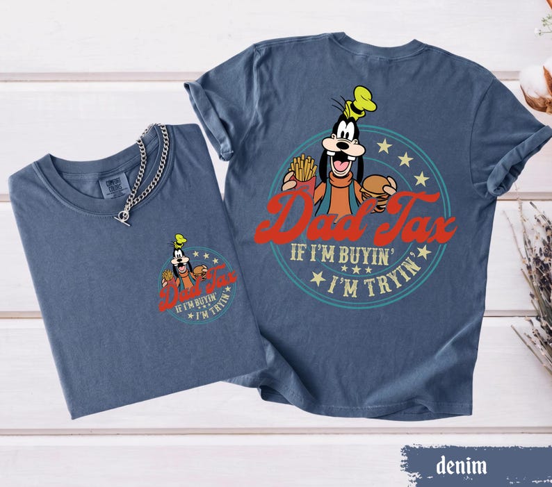May include: Two denim blue t-shirts. One shirt has a small graphic of Goofy with the text "Dad Tax" and "If I'm buyin', I'm tryin'". The other shirt has a larger version of the same graphic.