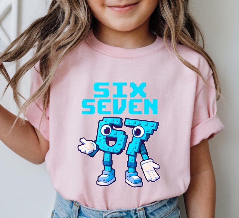 May include: A light pink t-shirt featuring the text "SIX SEVEN" in pixelated blue letters. Below the text are the numbers "67" designed as cartoon characters with blue bodies, white gloves, and blue shoes. The shirt is for children.
