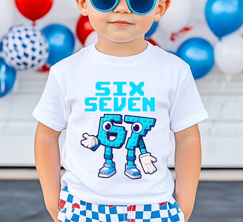 May include: White t-shirt with the words "SIX SEVEN" in pixelated blue font. Below the text are the numbers 6 and 7 designed as cartoon characters in blue, with white gloves and shoes. The shirt is worn by a child.